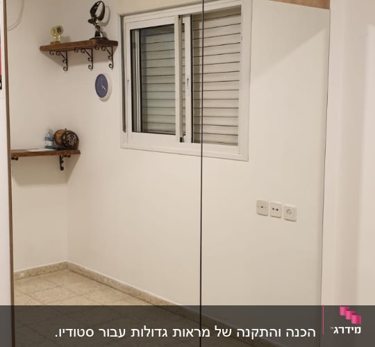 מראה גדולה עם מסגרת עץ על קיר לבן